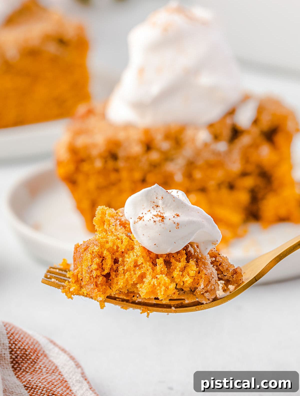 A close-up of a fork taking a bite of pumpkin coffee cake, showing its moist texture and the creamy whipped topping.