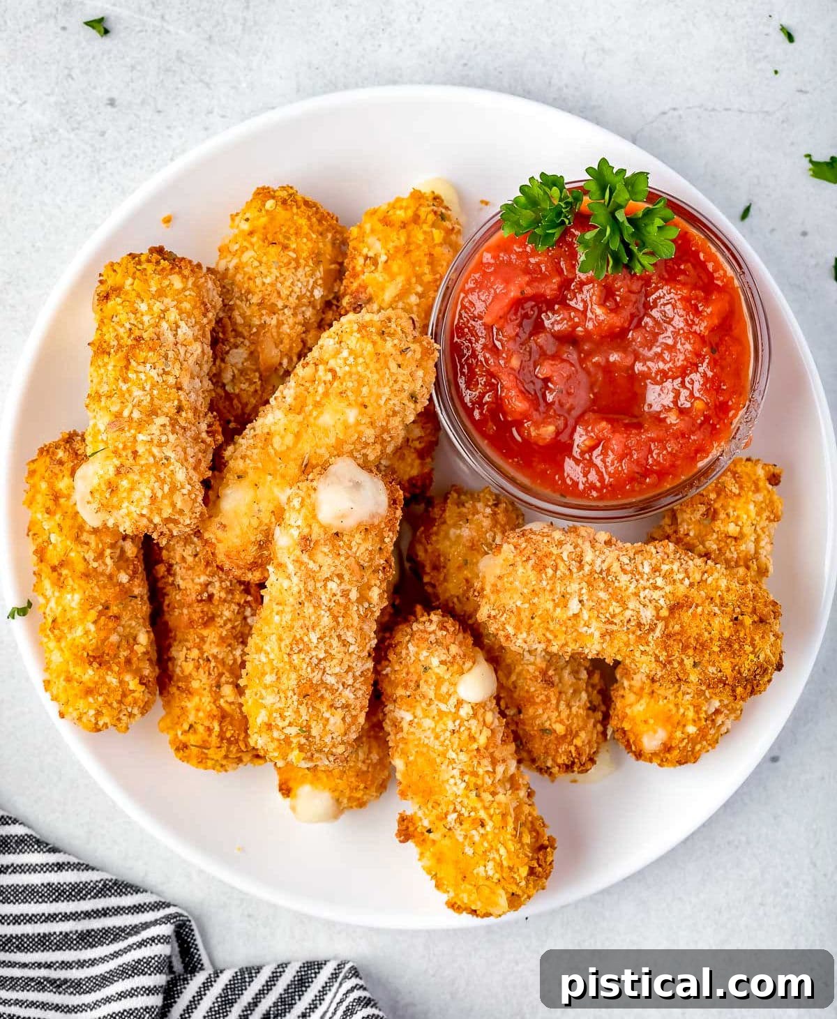 Golden & Gooey Air Fryer Mozzarella Sticks 4 A close-up view of three perfectly golden and crispy mozzarella sticks in an air fryer basket, captured mid-cooking, promising delicious results.