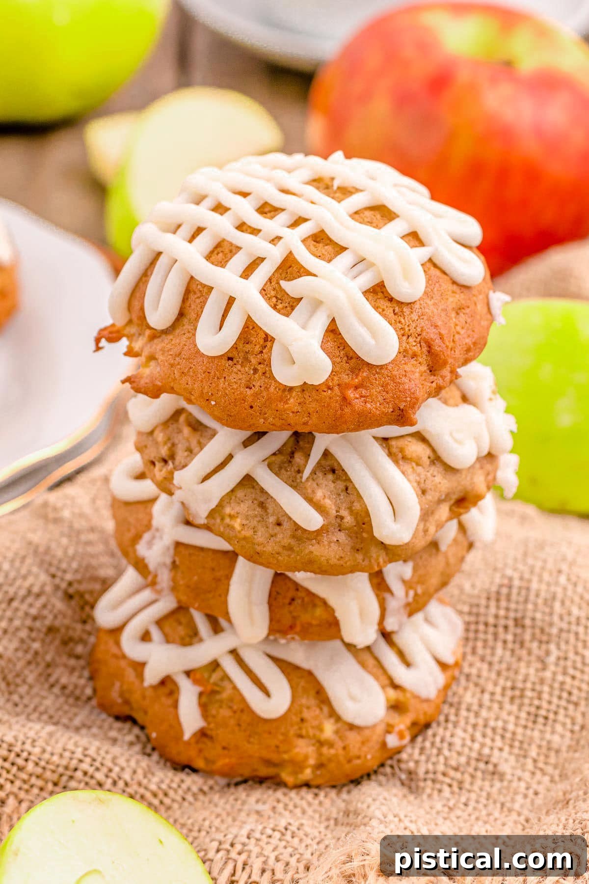 Three apple cookies, elegantly stacked, rest on a piece of burlap, showcasing their rich texture.