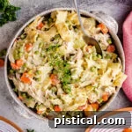 chicken and noodles recipe served in a stoneware bowl and topped with a sprig of thyme.
