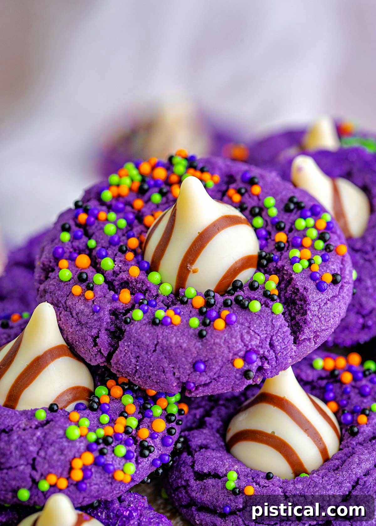 purple witch hat halloween cookies with sprinkles and hershey kisses pressed into the cookies.