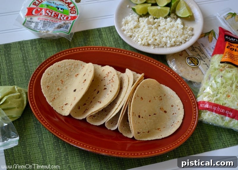 Ingredients laid out for building fish tacos: crispy fish, roasted corn salsa, tortillas, and toppings