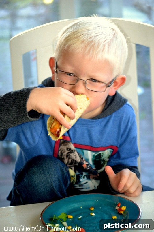 Young boy, Reece, happily eating a fish taco