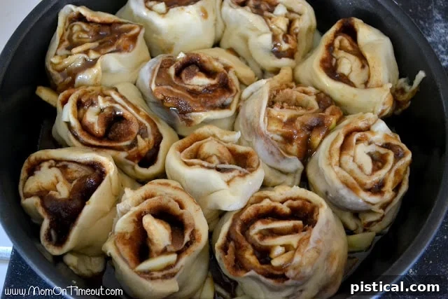 Sticky buns rising in a baking pan, covered with plastic wrap