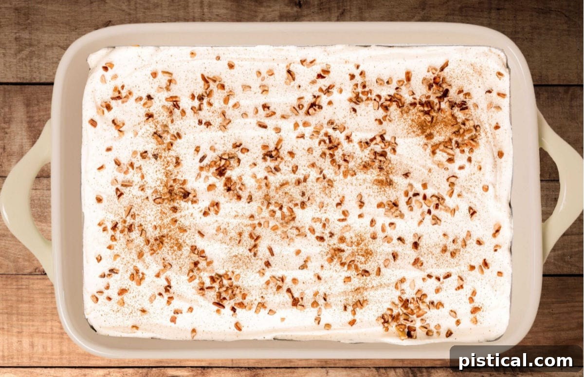Pumpkin Delight in a large baking dish, generously topped with whipped cream, toasted pecans, and a delicate dusting of pumpkin pie spice.