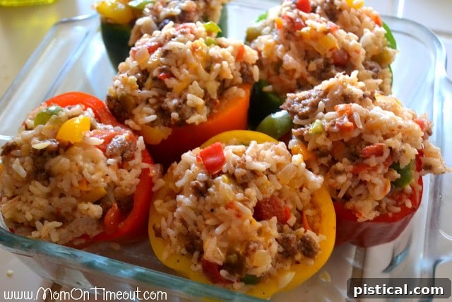 Stuffed bell peppers in a baking dish, topped with cheese and covered with foil