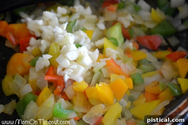 Sauteing chopped onions and bell peppers in a pan for stuffed pepper filling
