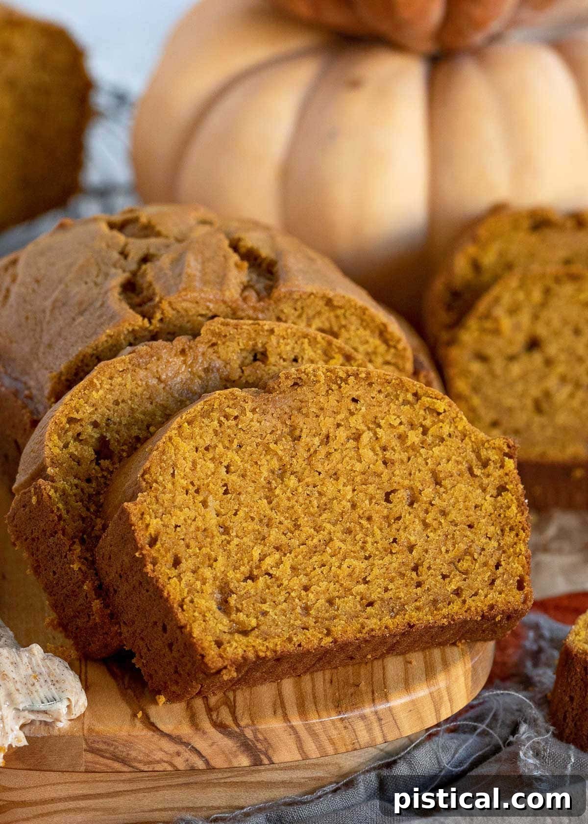 Ultimate Pumpkin Bread 3 Two generous slices of moist pumpkin bread lean against the main loaf, showcasing its tender crumb and inviting texture.