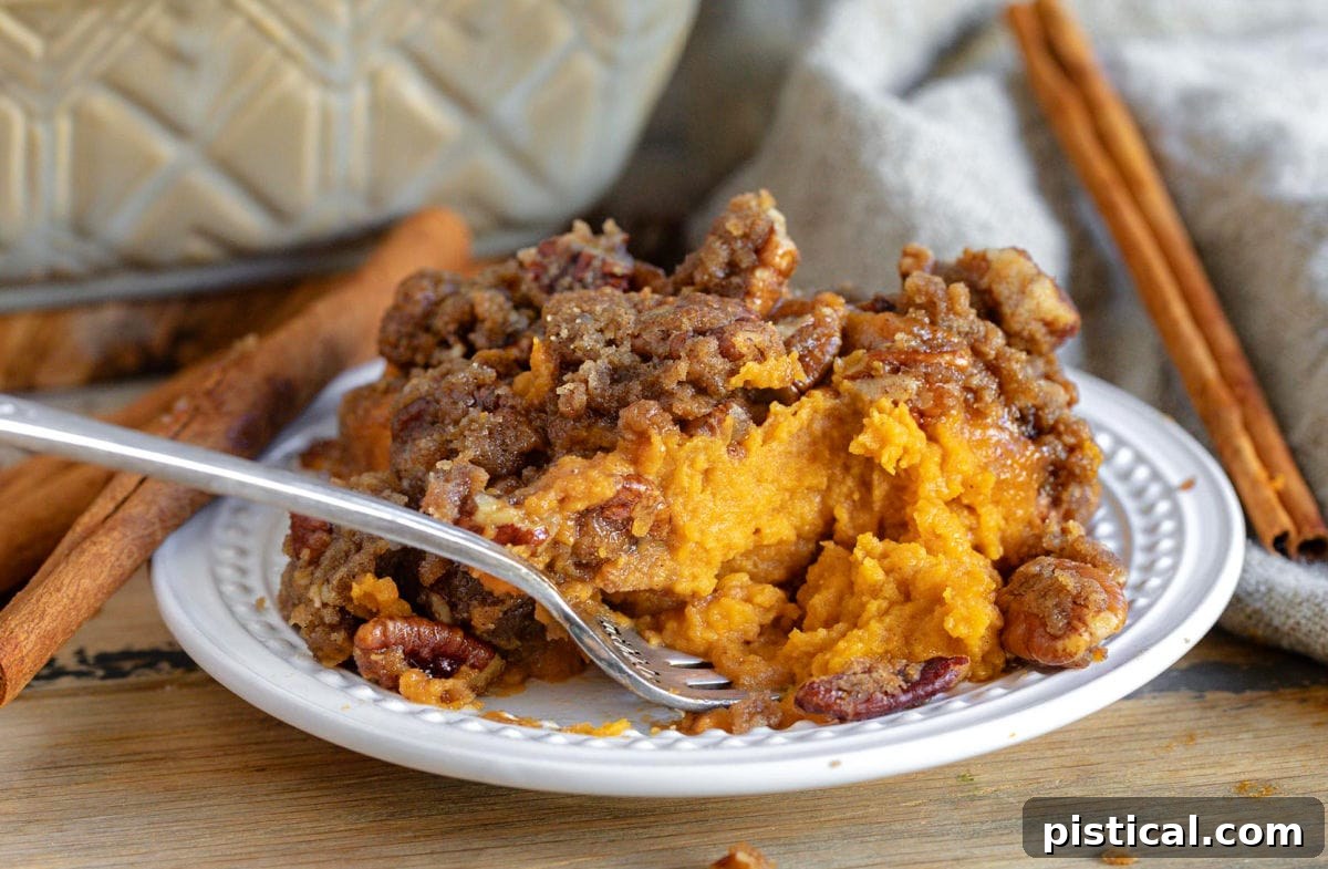 A small plate with a fork enjoying a mouthful of sweet potato casserole, demonstrating its deliciousness.