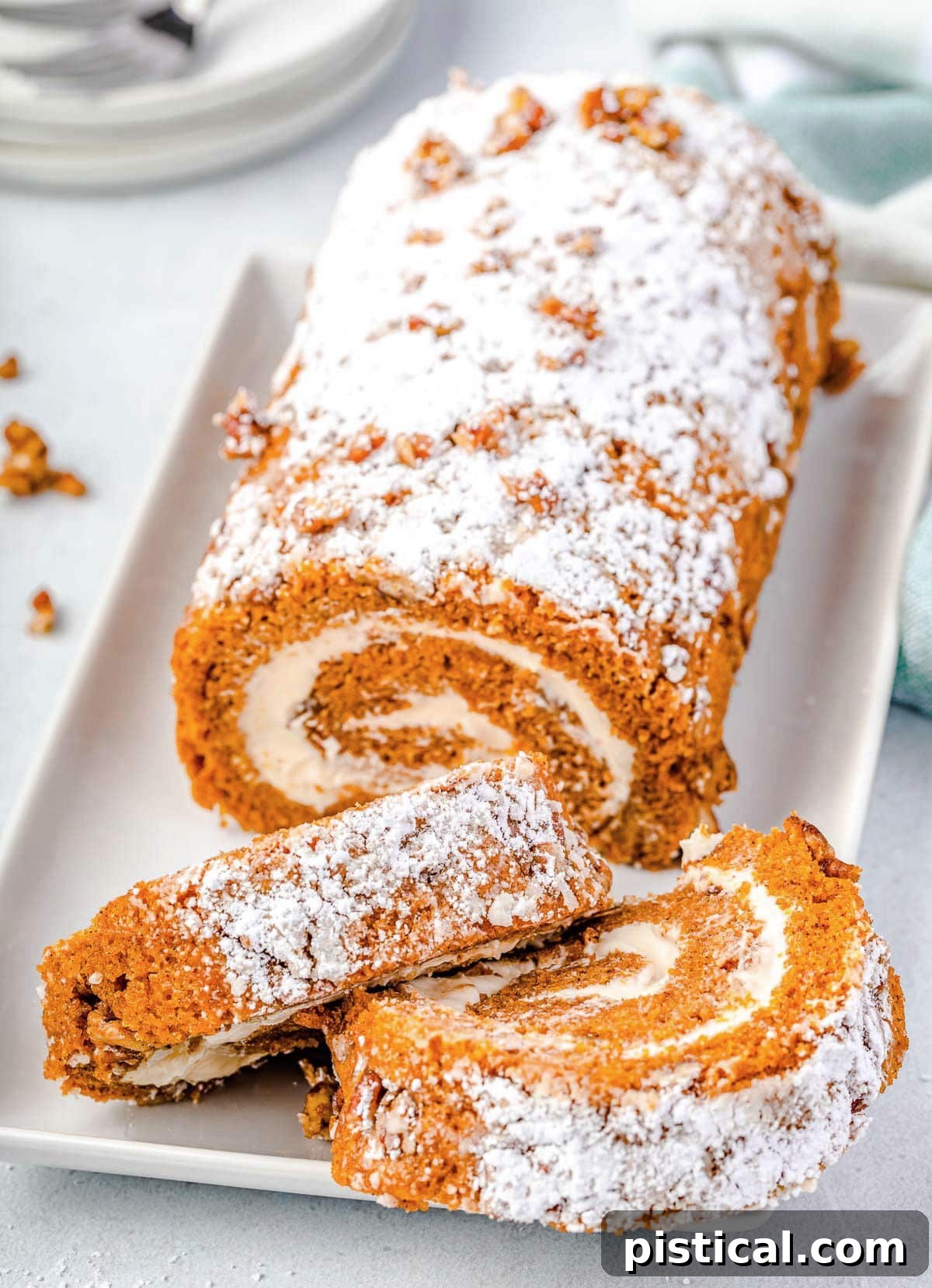 pumpkin roll with two slices cut off sitting on white rectangle serving plate.