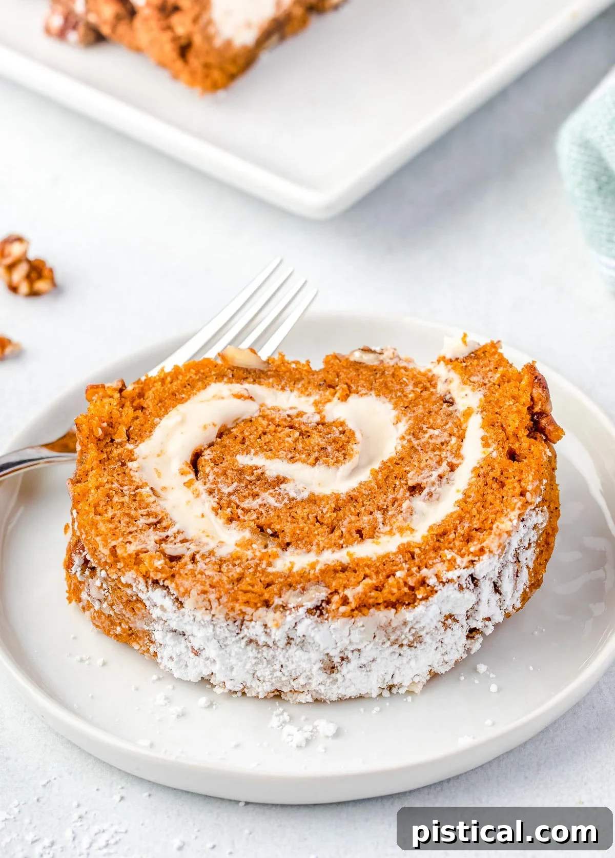 slice of pumpkin roll on a white plate with a small fork.