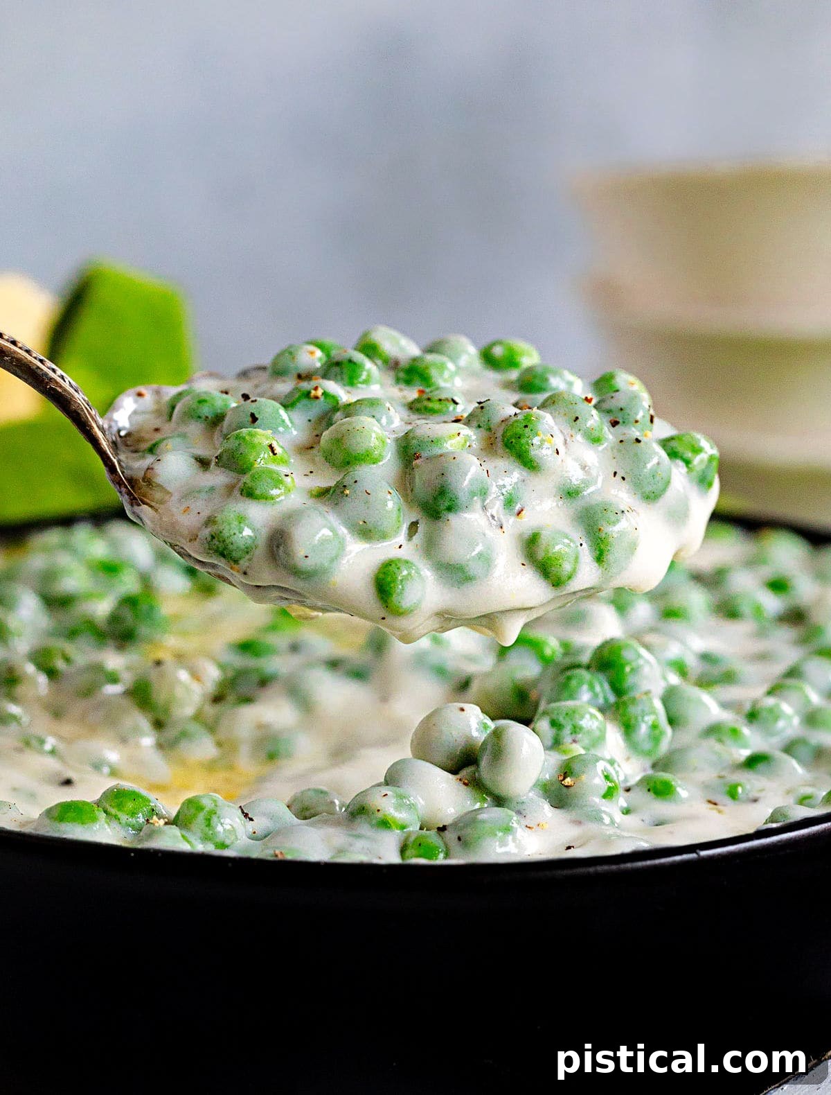 A large spoonful of homemade creamed peas, rich and ready to be served, showcasing the creamy texture and vibrant green peas.