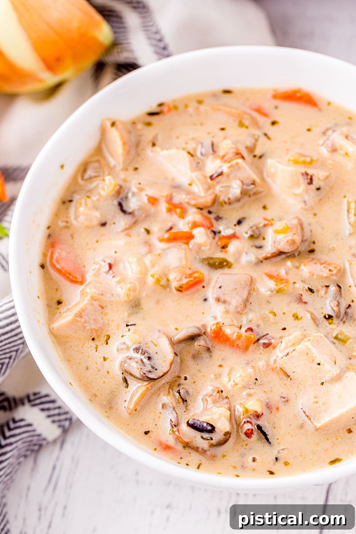 close up look at turkey soup with wild rice and mushrooms in a white soup bowl.