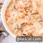 close up look at turkey soup with wild rice and mushrooms in a white soup bowl.