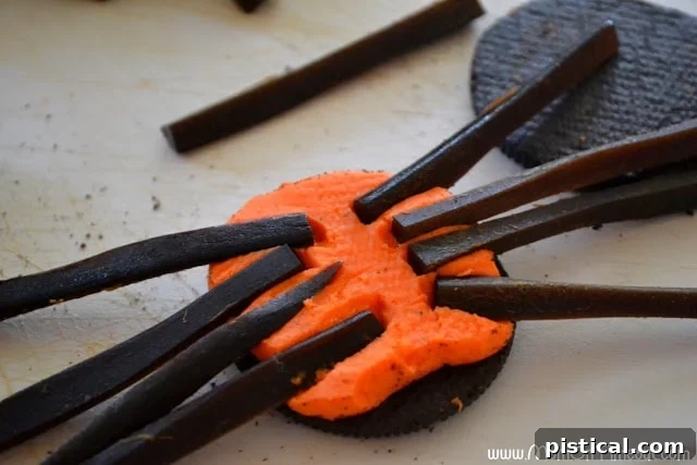Top Oreo wafer being placed back onto the bottom half with licorice legs, demonstrating gentle pressure
