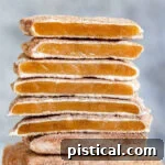 square churro toffee stacked on one another with several pieces broken in half so you see the toffee, the white chocolate layer and cinnamon sugar coating.