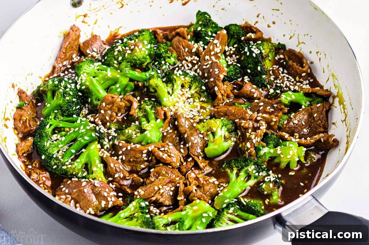 Savory Beef and Broccoli Stir-fry 3 beef and broccoli recipe still in the skillet with white interior. white sesame seeds sprinkled on top. ready to serve.