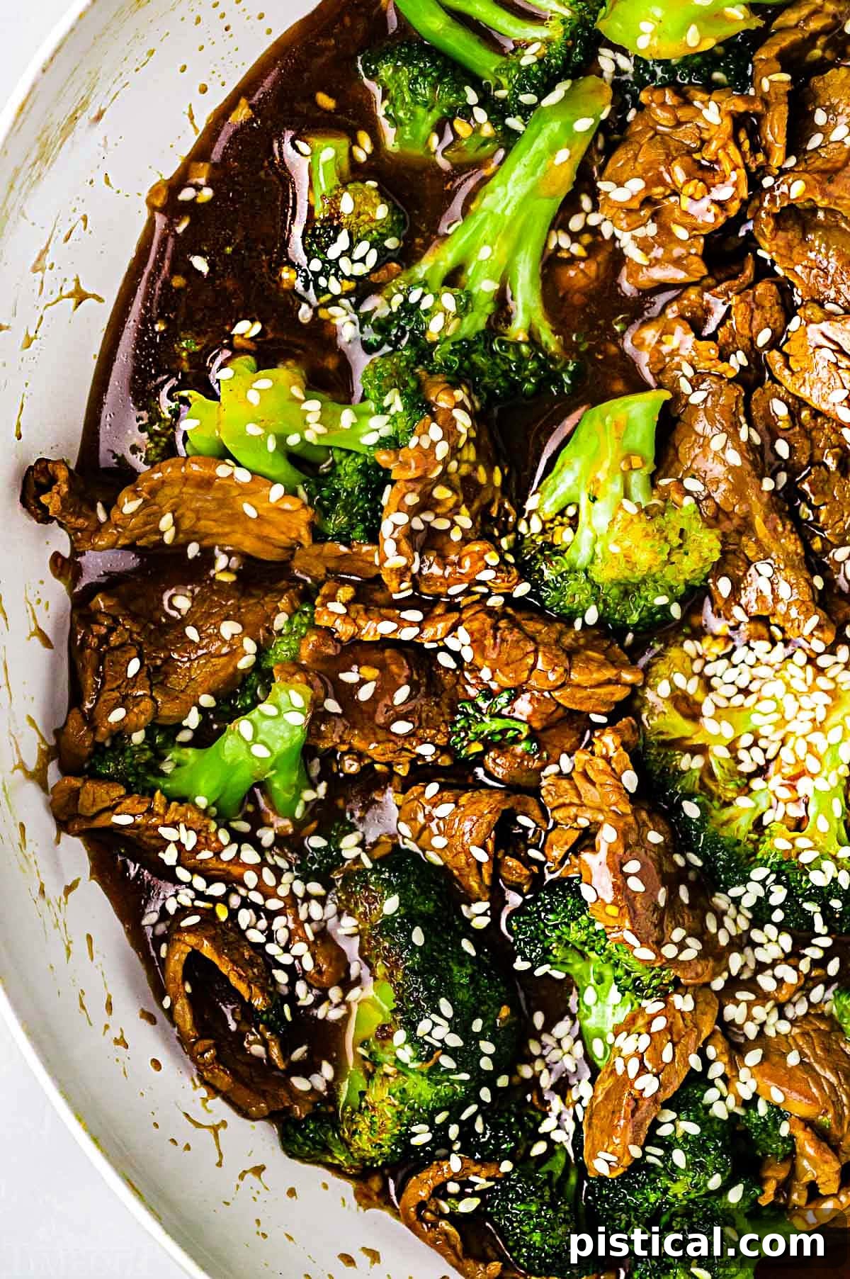 Savory Beef and Broccoli Stir-fry 4 top down look at beef and broccoli stir fry in a white skillet.