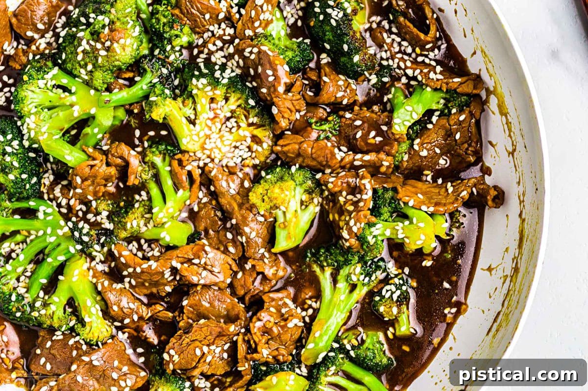Savory Beef and Broccoli Stir-fry 6 beef and broccoli stir fry recipe in white skillet topped with white sesame seeds. top down view.