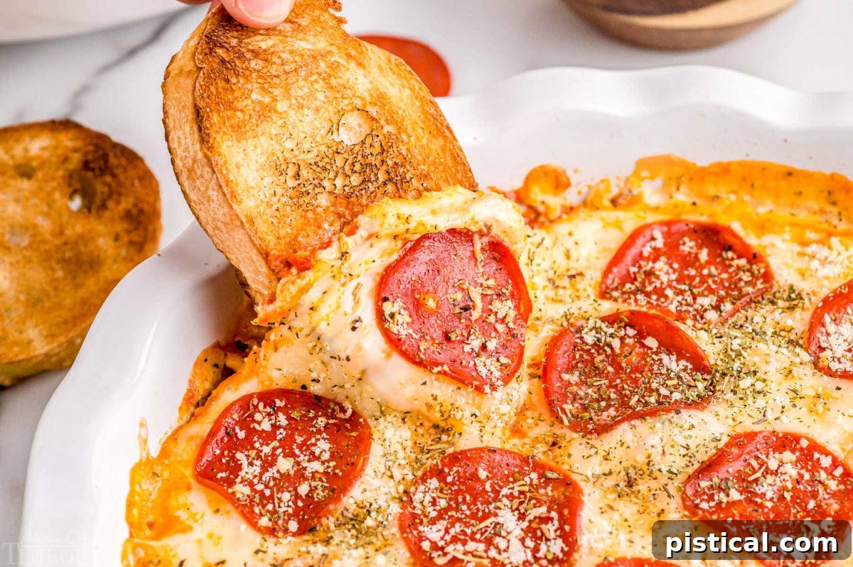 Ultimate Baked Pizza Dip 3 garlic bread being dipped into hot pizza dip topped with pepperonis.