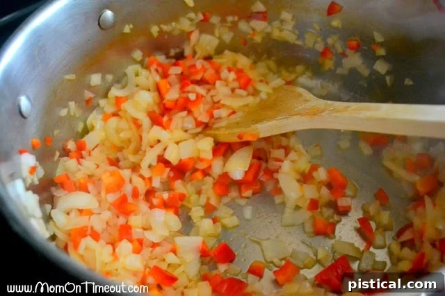 Onions, peppers, and garlic sautéing in a pot, the aromatic base for pasta sauce.