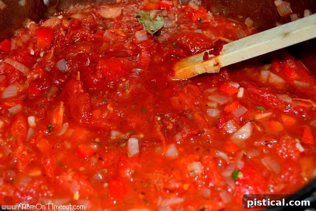 Homemade tomato pasta sauce simmering in a large pot, thickening to perfection.