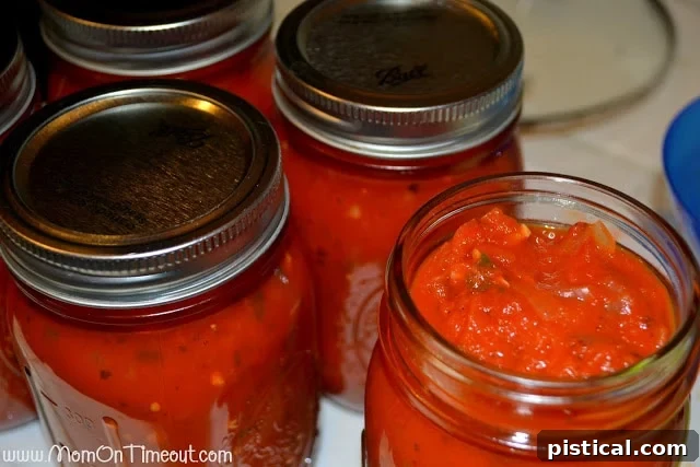 Glass jars of homemade pasta sauce processing in a boiling water bath canner.