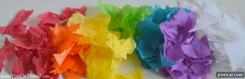 Kids tearing colored tissue paper into small pieces for a stained glass rainbow craft.