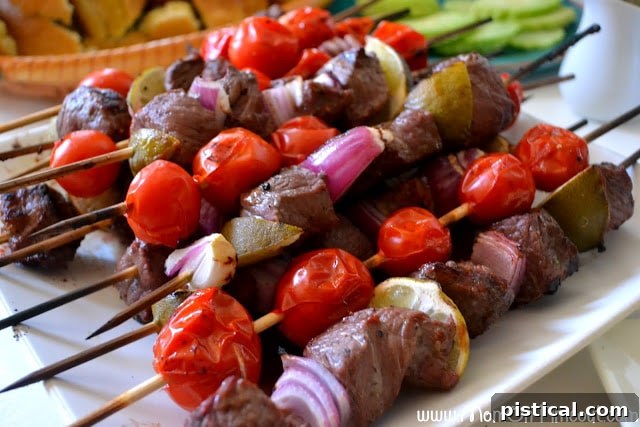 A vibrant spread of grilled Mojo Beef Kabobs, accompanied by fresh lime wedges and herbs on a rustic wooden board.