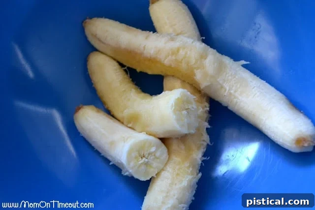 Three perfectly ripe bananas, ready for mashing, sitting in a vibrant blue mixing bowl.
