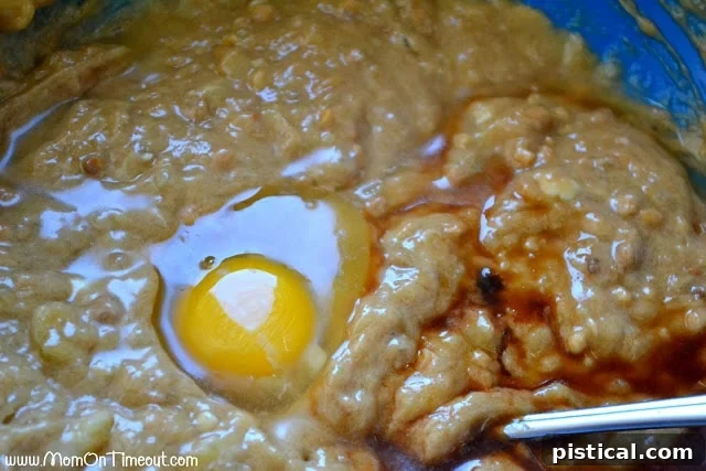 A close-up of the wet ingredients for peanut butter banana bread batter, with an egg and a dash of vanilla extract on top, ready to be mixed.