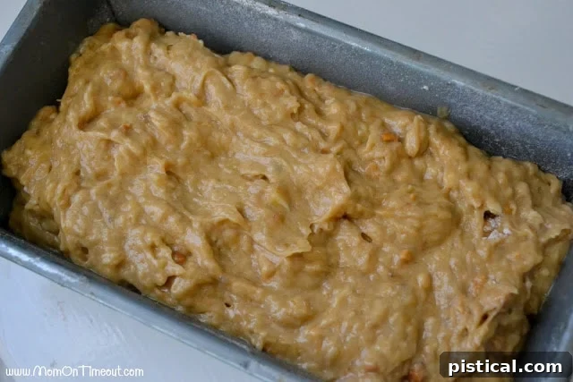 A greased and floured loaf pan filled with the thick, rich peanut butter banana bread batter, smoothed and ready for baking.