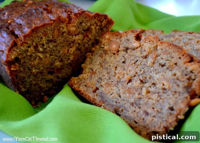 A delicious, golden-brown loaf of Peanut Butter Banana Bread, with two slices cut, resting on a green kitchen towel.