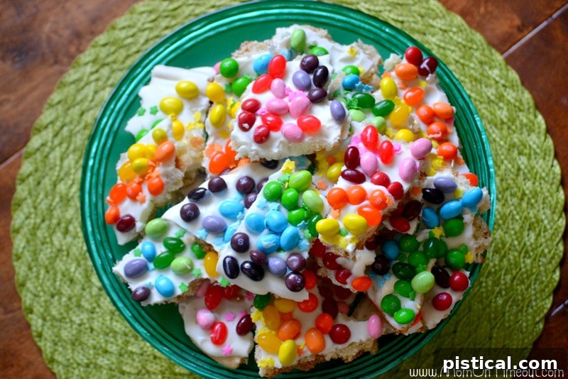 Beautifully broken pieces of Rainbow Sugar Cookie Bark on a cake plate, ready for serving. Top-down view of broken Rainbow Sugar Cookie Bark pieces arranged on a cake plate