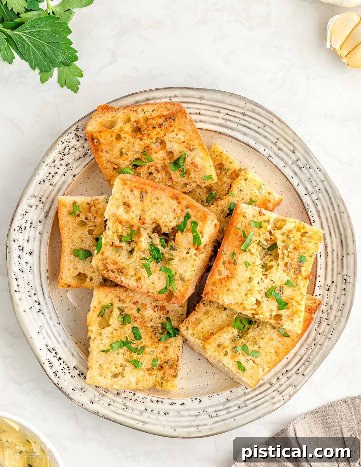 A top-down view of a white plate generously filled with perfectly golden Air Fryer Garlic Bread slices, ready to be enjoyed.