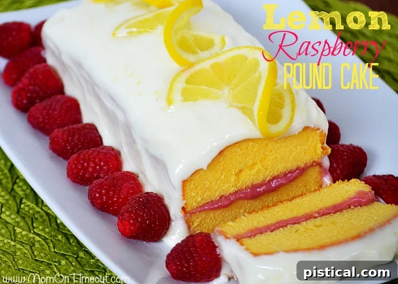 An overhead view of the Lemon Raspberry Pound Cake, showcasing the vibrant raspberry filling peeking through and the elegant lemon cream cheese frosting. Garnished with fresh lemon slices and raspberries.