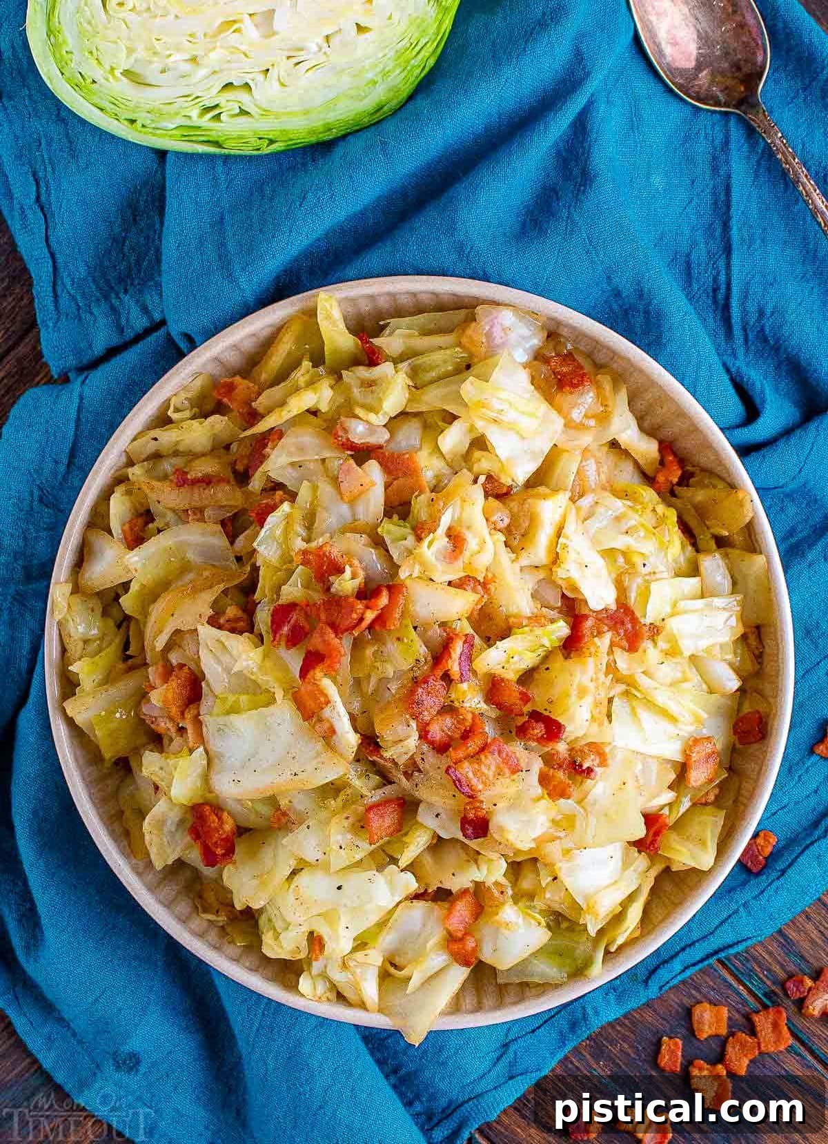 top down view of white plate filled with fried cabbage with bacon sitting on a teal napkin.