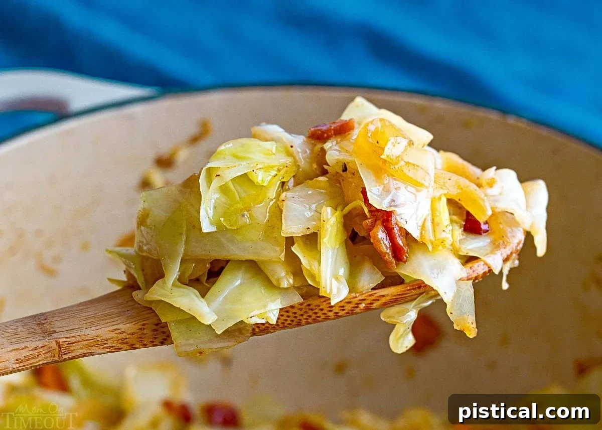 wooden spoon held over the pot of fried cabbage with a generous scoop of the fried cabbage.