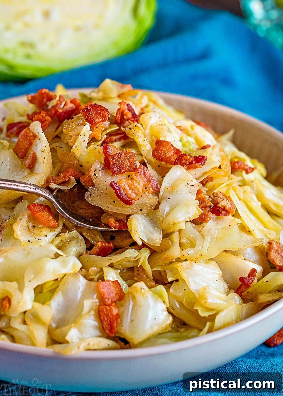 fried cabbage recipe in a white bowl with a spoon getting ready to take a bite stuck into the food.