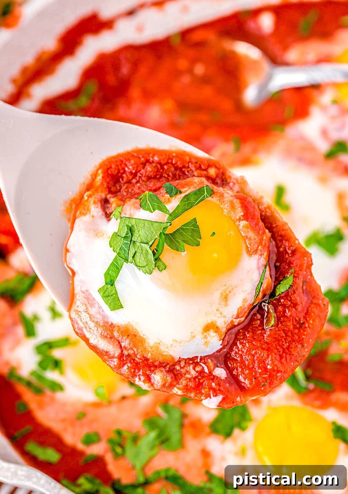 spoon held over skillet with a poached egg and sauce in it.