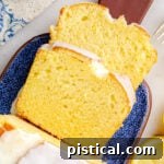 top down look at two slices of limoncello cake on a blue glazed clay cutting board. you can see the rest of the loaf and the glaze on top as well.