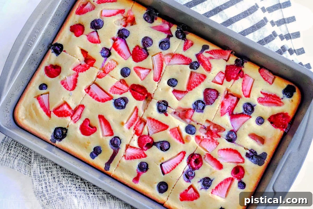 Oven pancakes, baked in a sheet pan and generously topped with fresh strawberries, raspberries, and blueberries, cut into ready-to-serve pieces.