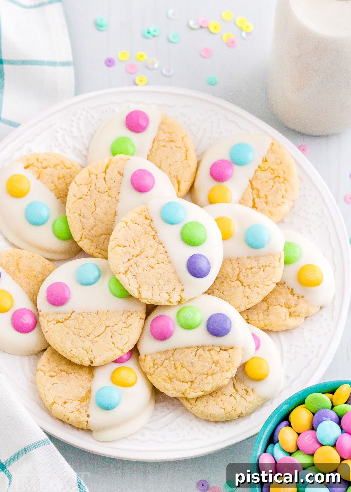 A white plate showcasing soft and chewy Easter Cake Mix Cookies, dipped in white candy melts and decorated with three pastel M&M's to resemble a charming bunny paw print. Perfect for a quick and easy Easter dessert.