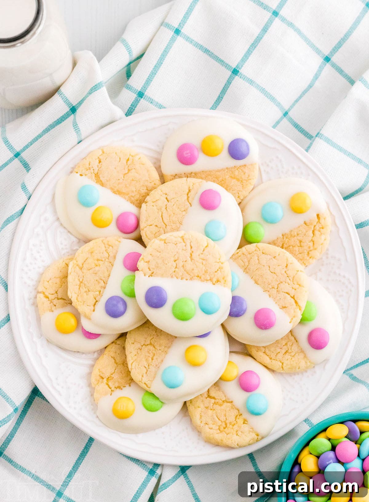 A white plate showcasing soft and chewy Easter Cake Mix Cookies, dipped in white candy melts and decorated with three pastel M&M's to resemble a charming bunny paw print. Perfect for a quick and easy Easter dessert.