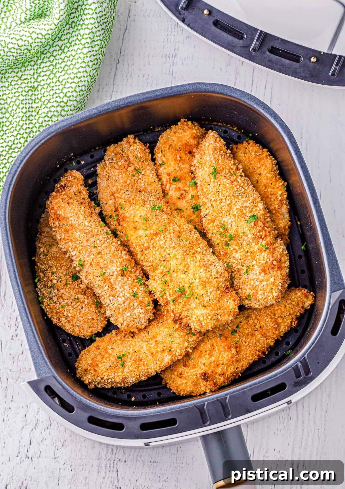 Top-down view of perfectly cooked air fryer chicken tenders arranged in an air fryer basket.