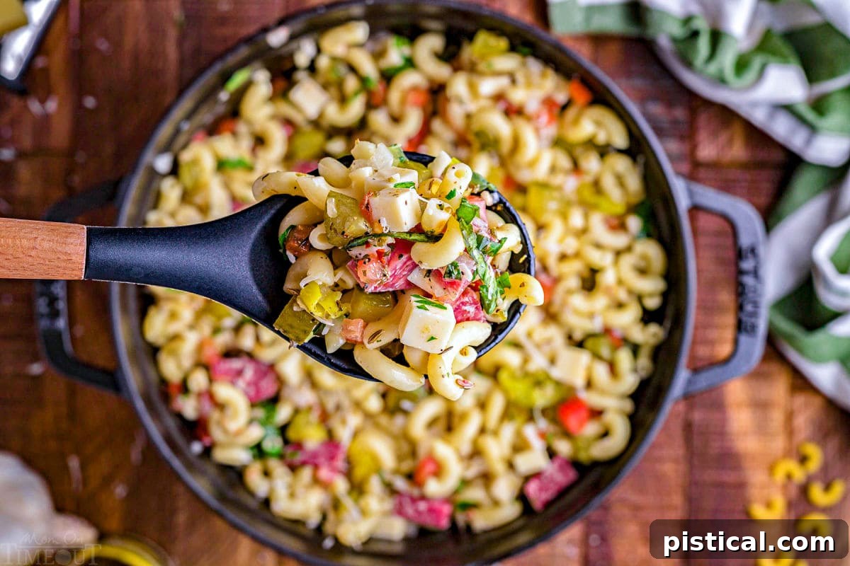 A serving spoon gracefully lifts a vibrant portion of Italian pasta salad above the elegant black serving dish, showcasing the medley of colorful ingredients coated in dressing.