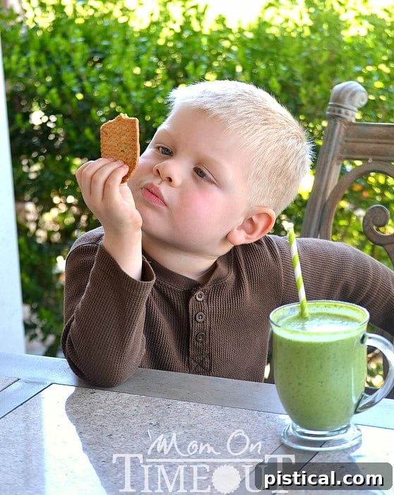 Smiling child, Bryce, happily drinking a green smoothie, demonstrating how much kids enjoy these healthy breakfast options.