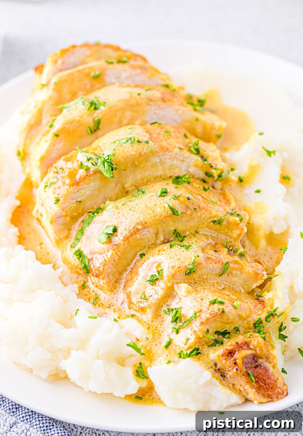 Close-up of perfectly sliced honey mustard chicken breast resting on a bed of creamy mashed potatoes, ready to be enjoyed.