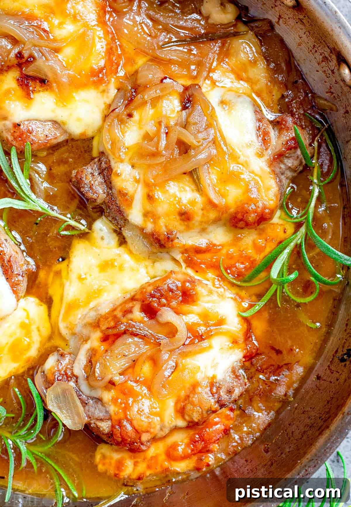 top down look at pork chops in skillet made with French Onion soup flavors. Melted cheese is browned on top.