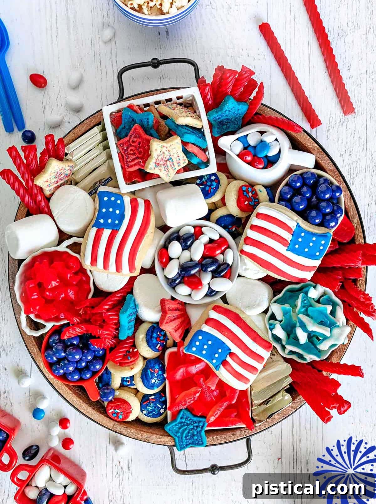 Red, White & Blue Grazing Board 2 top down look at wood charcuterie board loaded with red white and blue desserts for 4th of july. cookies, candy and all sorts of colorful treats.